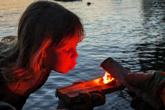 Child helping start a fire on Flagstaff Lake