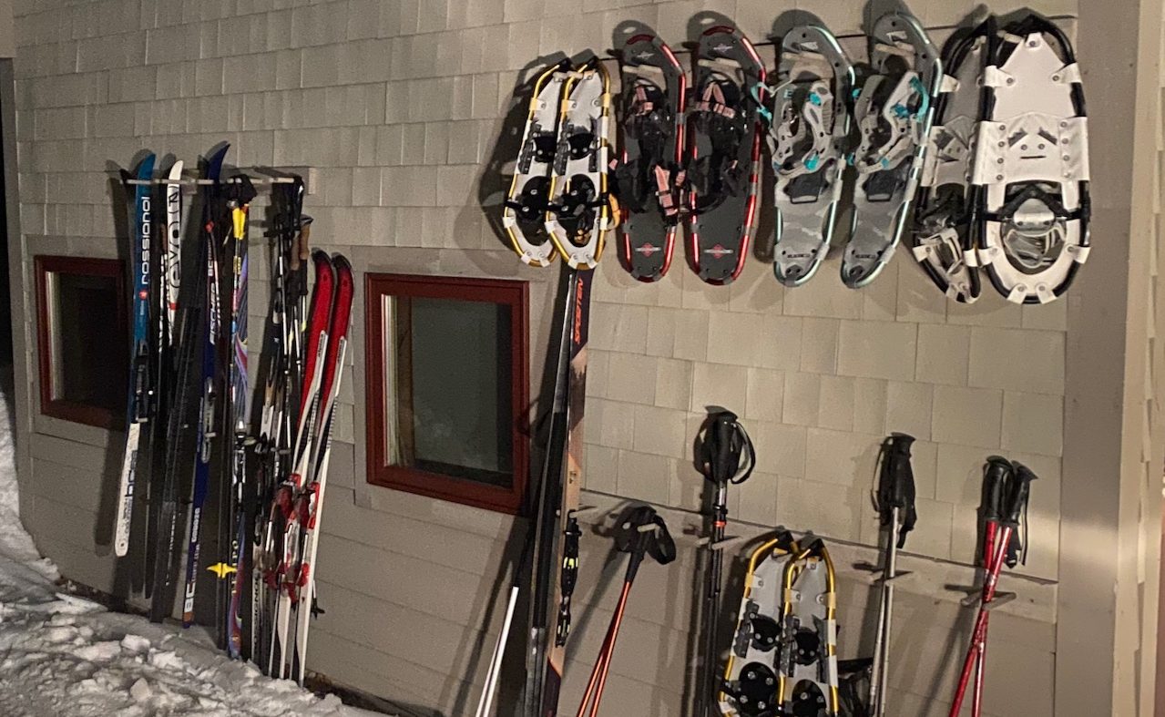 Poplar Hut outside at night with snowshoes and cross country skis.