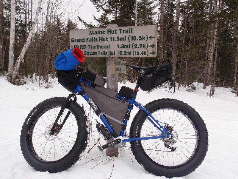 Winter fat bike leaning against a trail sign.