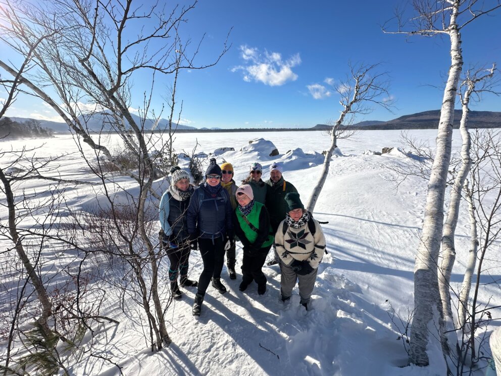 Group on the shore of Flagstaff Lake Hut in winter.