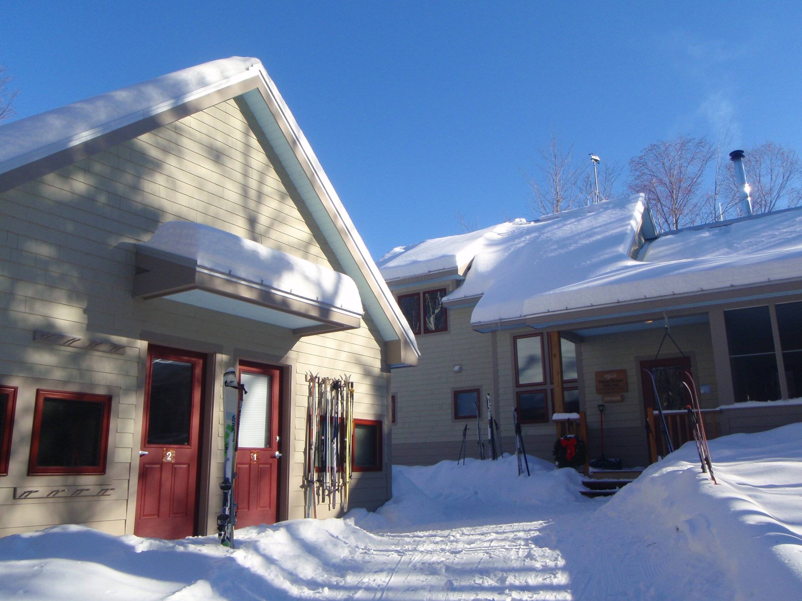 Outside of Poplar Stream hut with guest skis in the snowbanks.