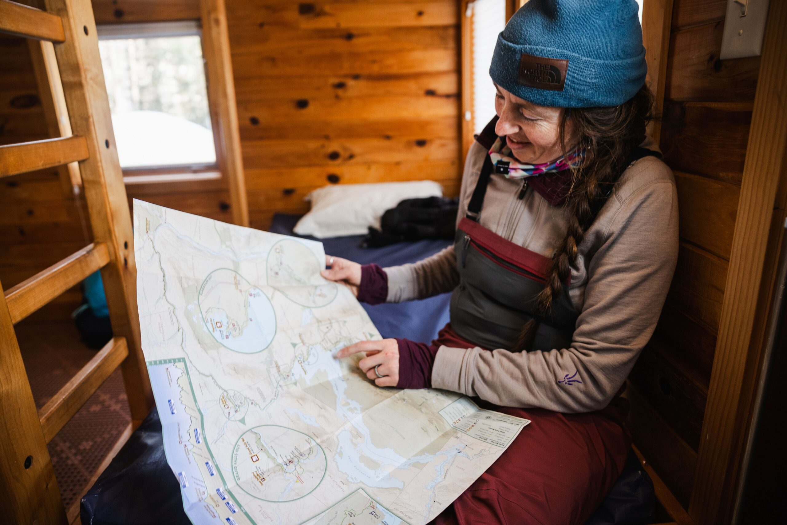 Guest reading the Maine Huts & Trails map in a bunkroom.