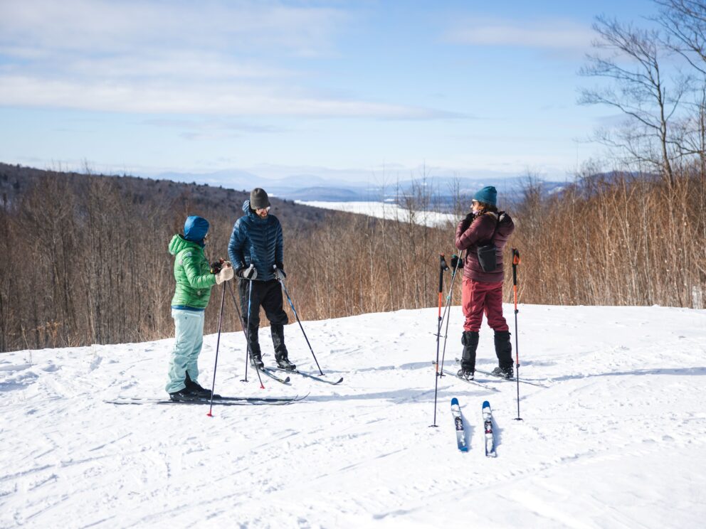 Skiers at the scenic Overlook Vista with views of Flagstaff Lake and mountains in the background.