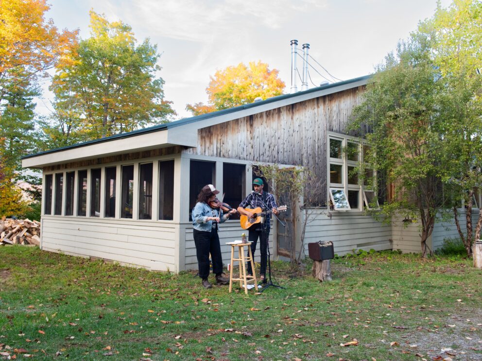 Band Landline playing string instruments outside Stratton Brook Hut
