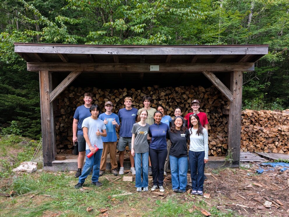 Bowdoin College volunteer wood stacking.